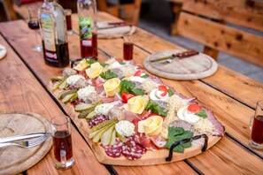 Una mesa de madera con una tabla de embutidos que presenta diversas carnes, quesos y guarniciones.