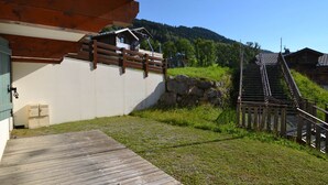 A wooden deck leading to a building with a stone wall and a metal staircase. - Ski-in/ski-out apartment with terrace, pet-friendly, Flumet (Flumet)