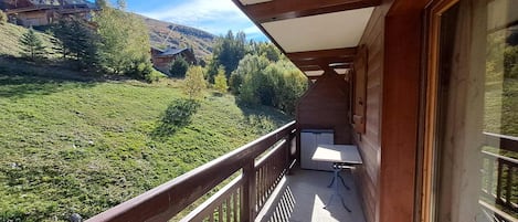 A balcony with a view of a green landscape and a building in the distance.