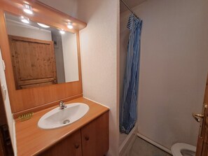 A bathroom with a wooden vanity, a white sink, a mirror, and a striped shower curtain.