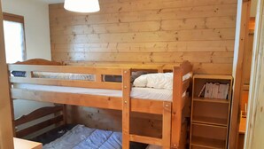 Ein Schlafraum mit Etagenbetten, Holzwänden und einem Bücherregal.