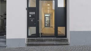 Una entrada moderna con puerta de cristal, teclado numérico y letrero con el número 4.