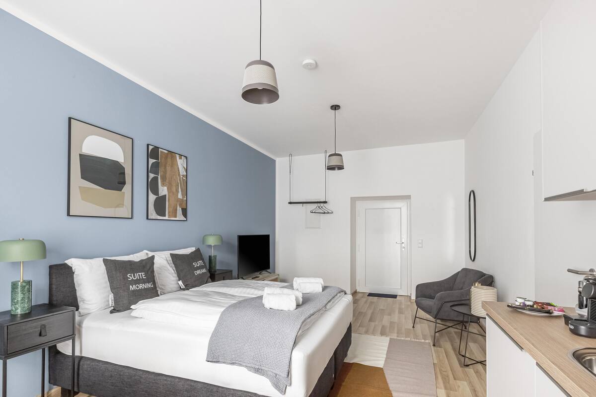 A modern bedroom with a large bed, bedside tables, a desk, and a chair.
