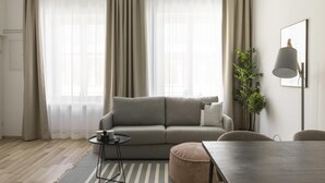 Un salón moderno con un sofá gris, una mesita redonda, una alfombra a rayas y una mesa de comedor.