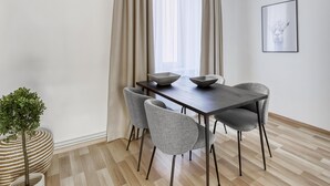 Un comedor moderno con una mesa de madera oscura, cuatro sillas grises y dos cuencos blancos.