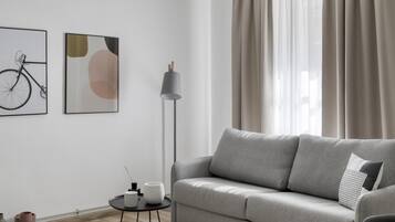 Una sala de estar moderna con un sofá gris, una lámpara de pie y dos cuadros abstractos colgados en la pared.