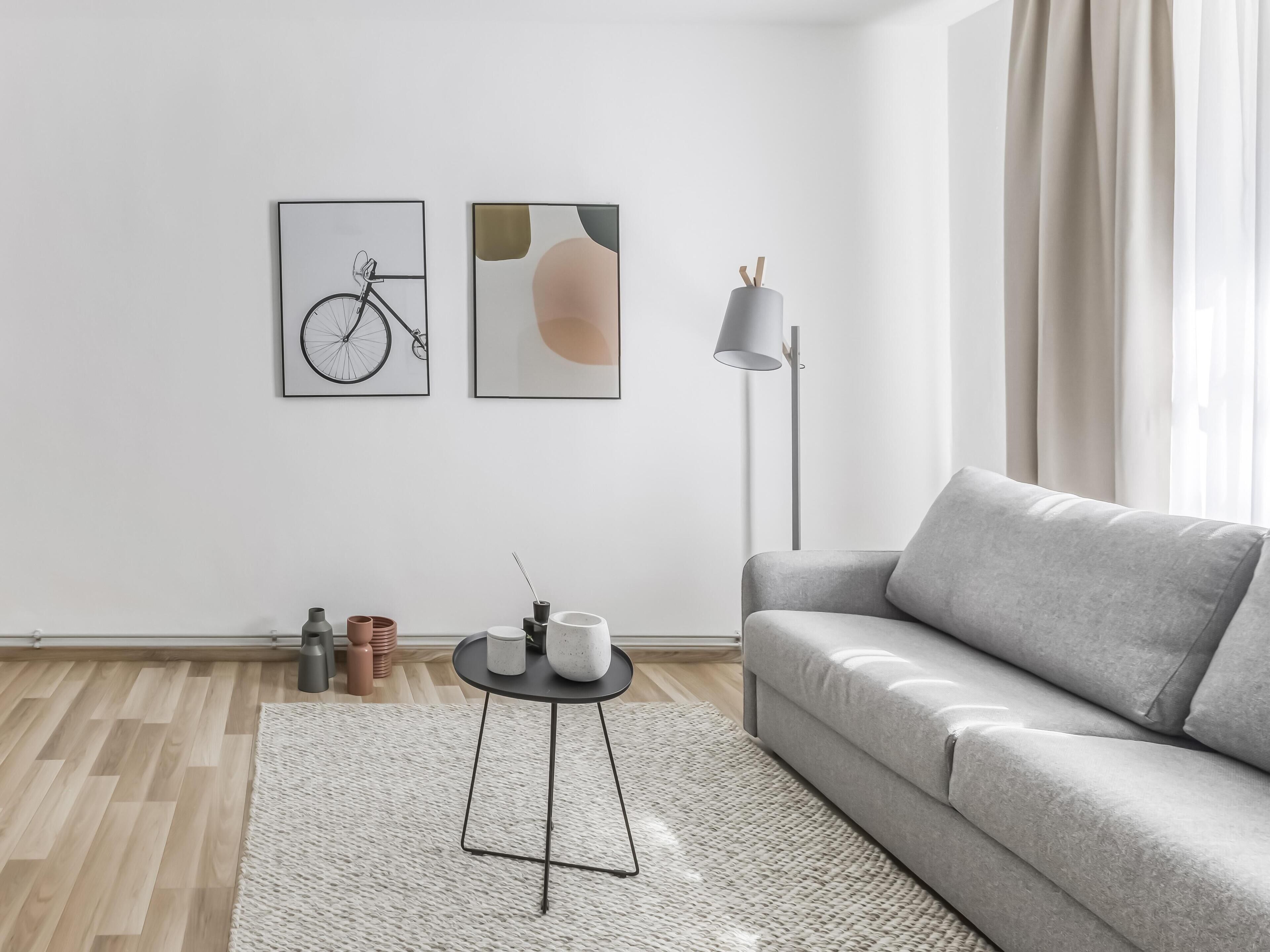 A modern living room with a grey sofa, a round coffee table, and two wall-mounted artworks.
