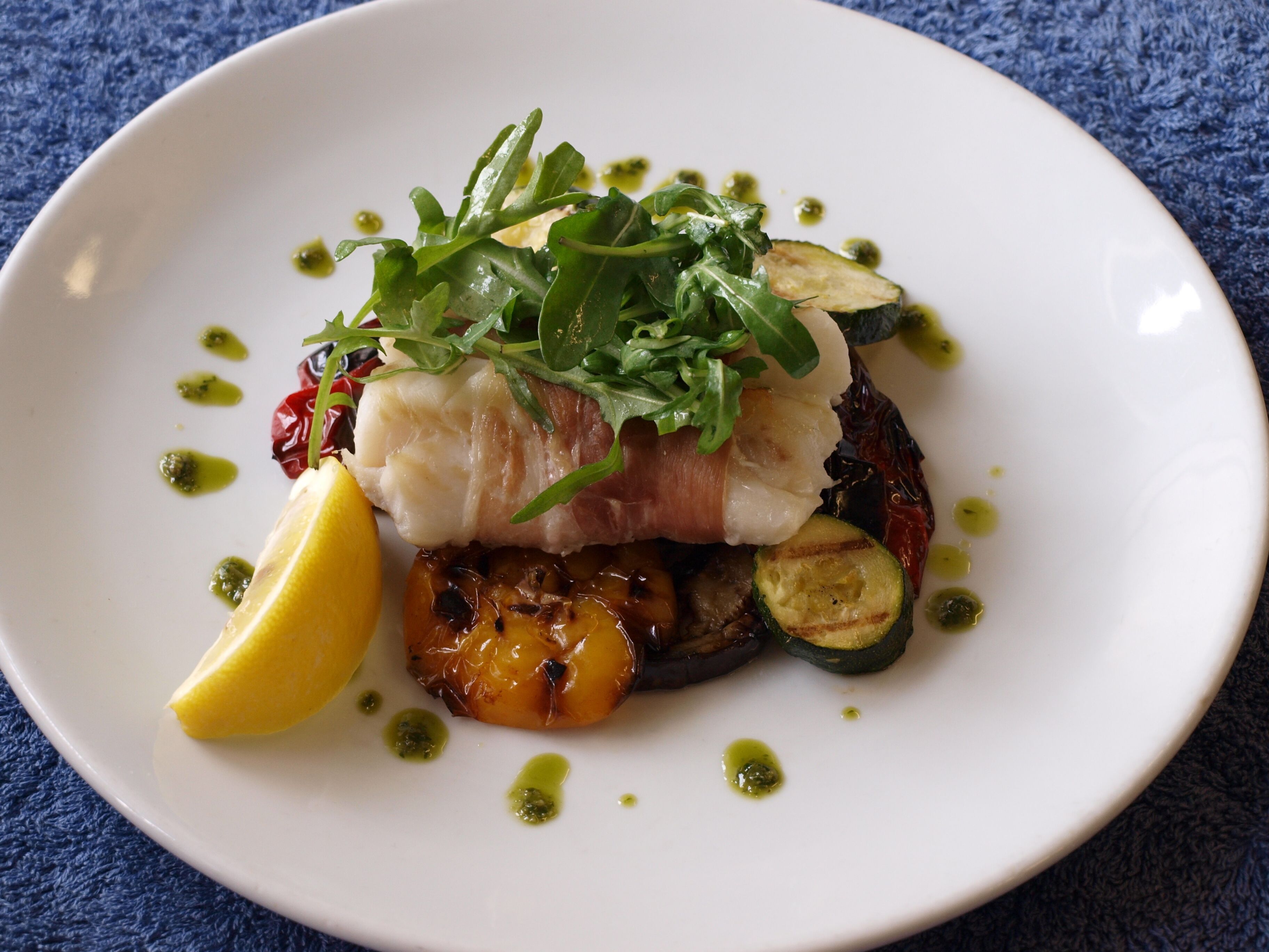 A plate of food with fish, vegetables, and a lemon wedge.