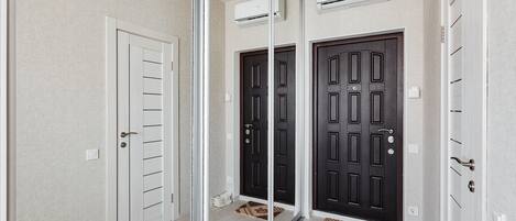 Um corredor com uma porta de vidro, duas portas pretas e uma porta branca. Há unidades de ar condicionado nas paredes.
