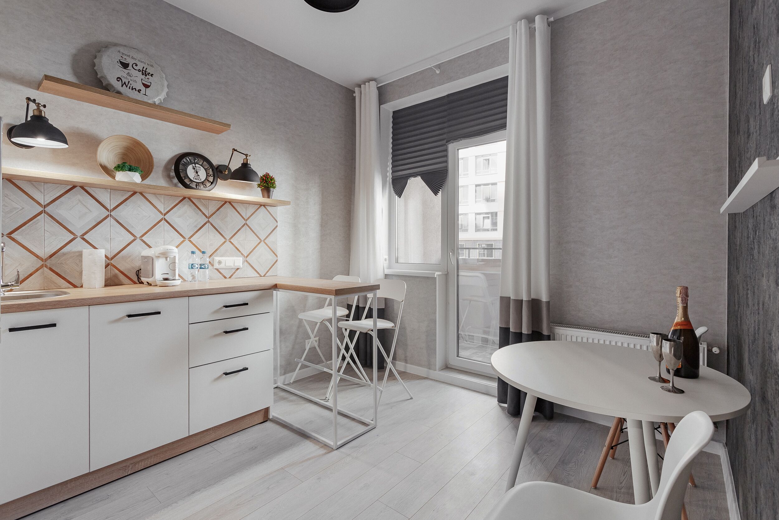 Une cuisine moderne avec des meubles blancs, un plan de travail en bois et un coin repas comprenant une table et des chaises blanches.