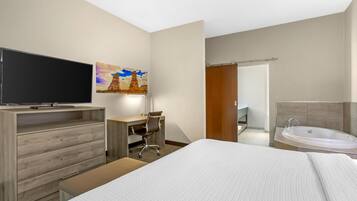 A hotel room with a bed, a desk with a chair, a television, a painting, a bathroom with a bathtub, and a shower.