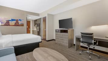 Een hotelkamer met een bed, een bureau met stoel, een televisie en een schilderij aan de muur.