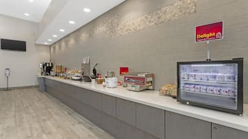 A self-service yogurt and pastry station with a refrigerated display, a coffee machine, and a variety of condiments.