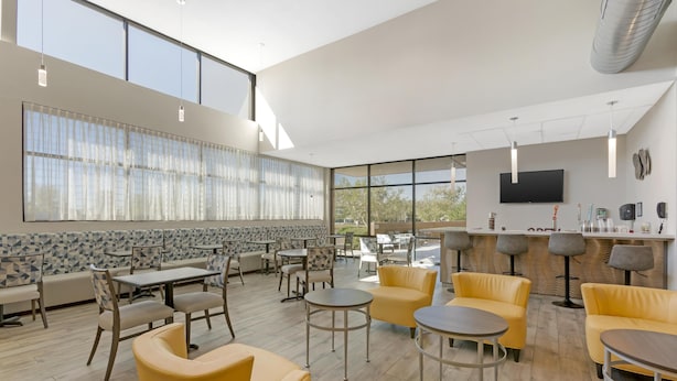 A spacious indoor area with multiple seating options including tables and chairs, a bar area with stools, and large windows providing natural light. - Best Western Plus Executive Residency Phoenix North Happy Valley (Phoenix)