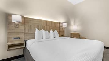 A hotel room with a large bed, two bedside tables, a wooden headboard, and wall-mounted lamps.
