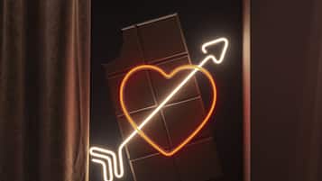 A neon sign with a heart and arrow design.