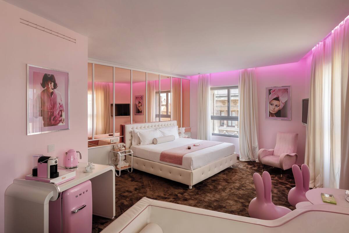 A pink-themed bedroom with a bed, bedside tables, a chair, and a desk.