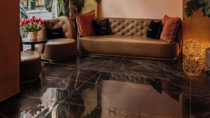 Um saguão de hotel com um lustre moderno, um sofá com almofadas, uma planta em vaso e uma placa para ODSweet Duomo Milano Hotel.