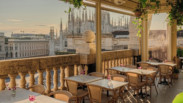 Terraço com mesas e cadeiras, com vista para um edifício histórico.
