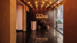 Um lobby de hotel moderno com design geométrico no chão, um balcão de recepção e uma grande janela com vista para o exterior.