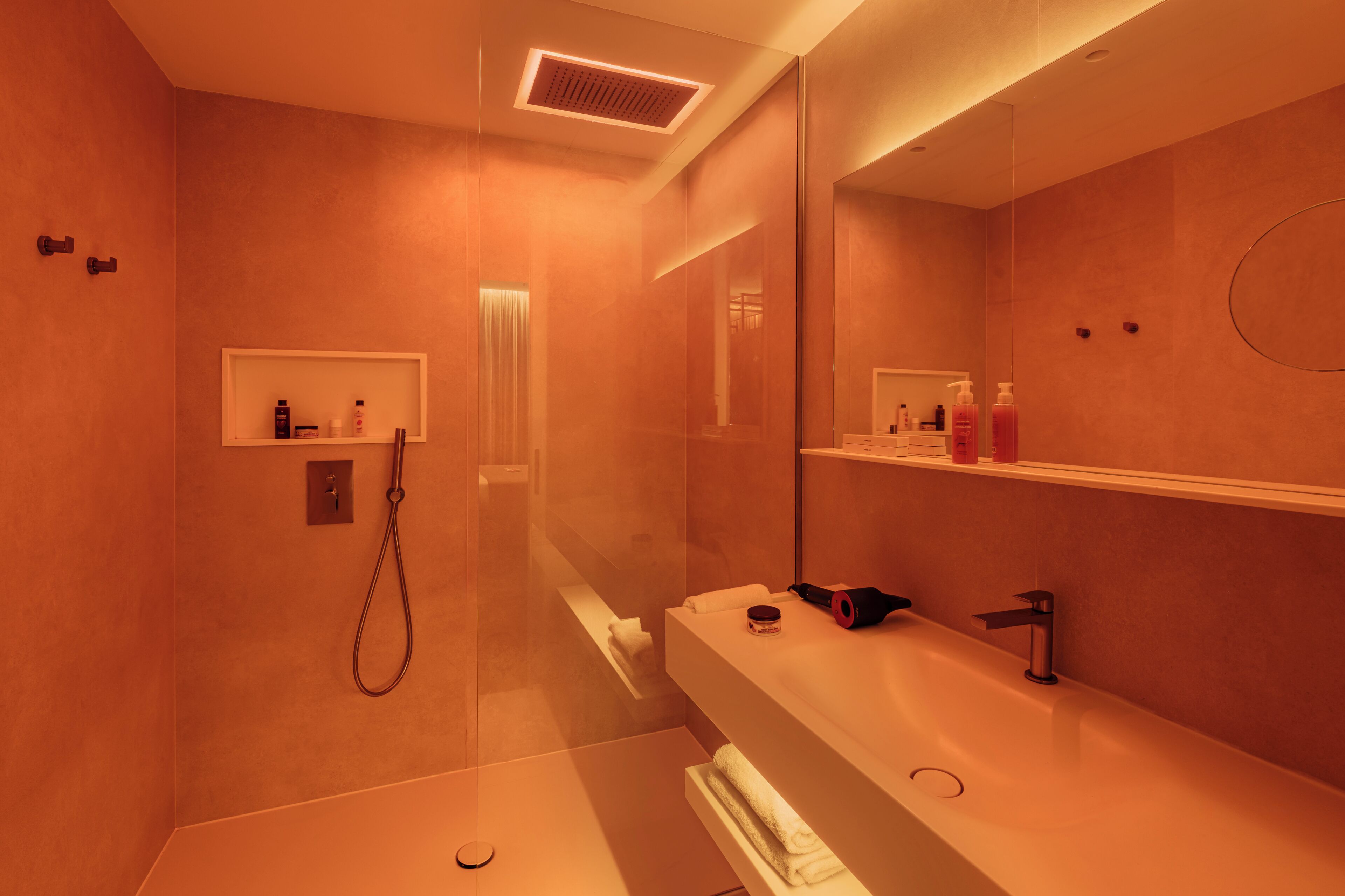 A modern bathroom with a large mirror, a shower, and a vanity with a sink.