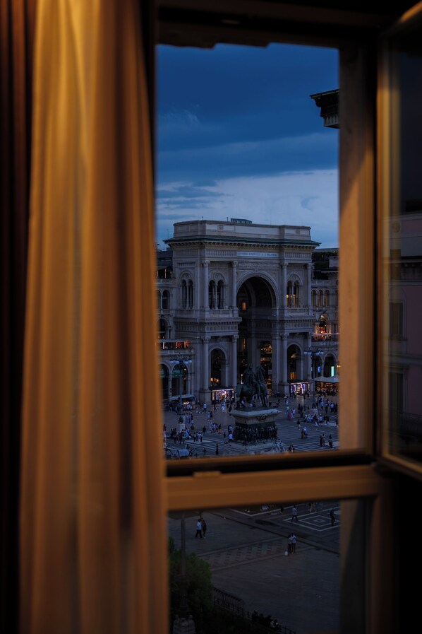 A view through a window of a historic building with an open plaza and a statue in the center.