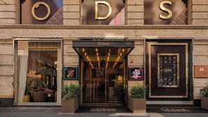 El exterior del Hotel ODS con un gran letrero iluminado 'ODS', una entrada de vidrio y una exhibición con temática de chocolate.