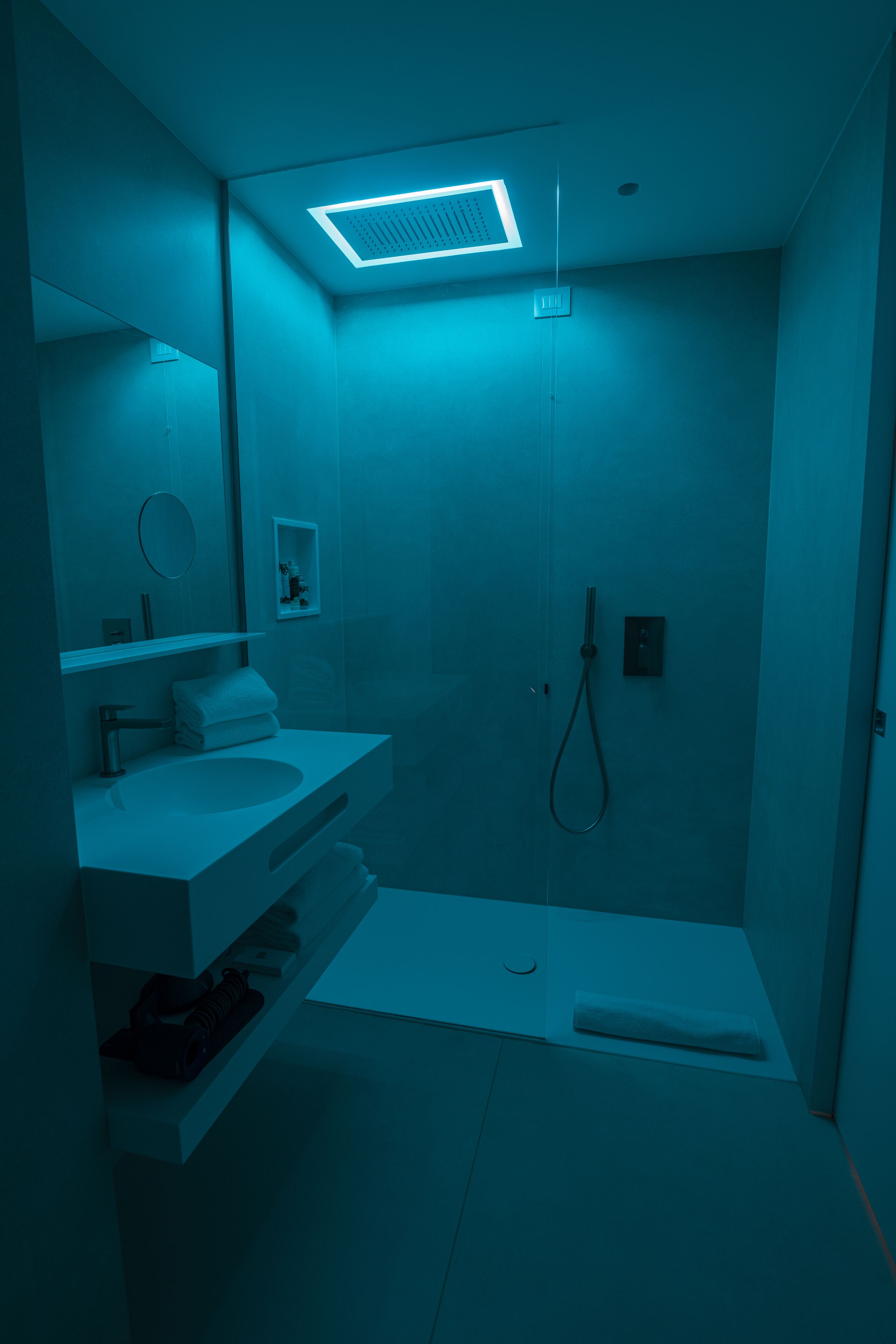 A modern bathroom with a white sink, mirror, and shower.
