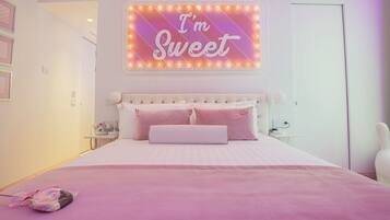 Una camera da letto con un letto, un neon con la scritta 'I'm Sweet' e una coperta rosa.
