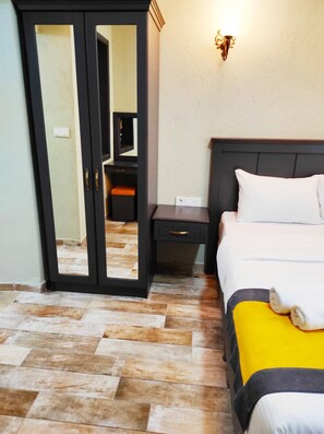 Ein Hotelzimmer mit einem Bett, einem Nachttisch und einem Kleiderschrank.