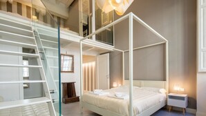 Ein Schlafzimmer mit Himmelbett, einer Glastreppe und einem Nachttisch mit Lampe.