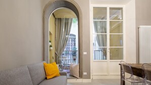 Ein Wohnzimmer mit grauem Sofa, einem Holztisch und einer Glastür, die auf einen Balkon führt.