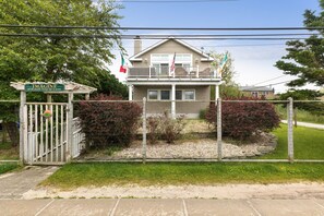 A two-story house with a balcony, surrounded by a fence and a sign that reads "IMAGINE". - Kismet, 4 bedroom Fire Island family house "IMAGINE" (Kismet)