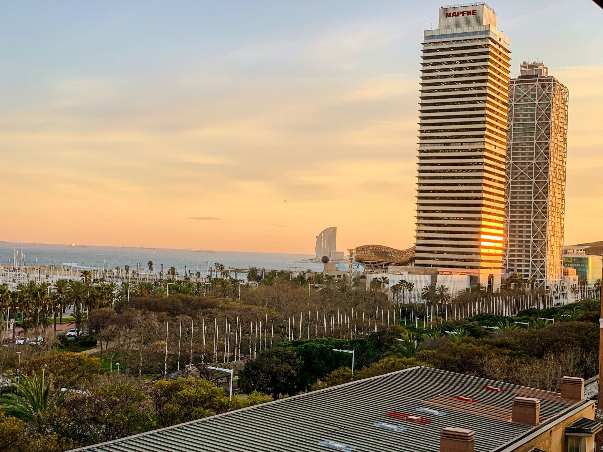 A high-rise building with a modern architectural design, surrounded by a marina and palm trees.
