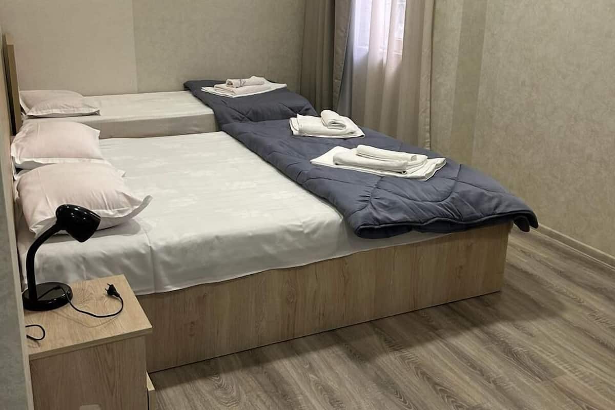 Una habitación de hotel moderna con una cama grande, una mesita de noche con lámpara y un equipo de aire acondicionado en la pared.