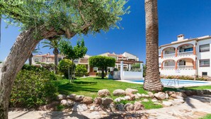 Zona residencial con piscina, sendero de piedra y un árbol grande.