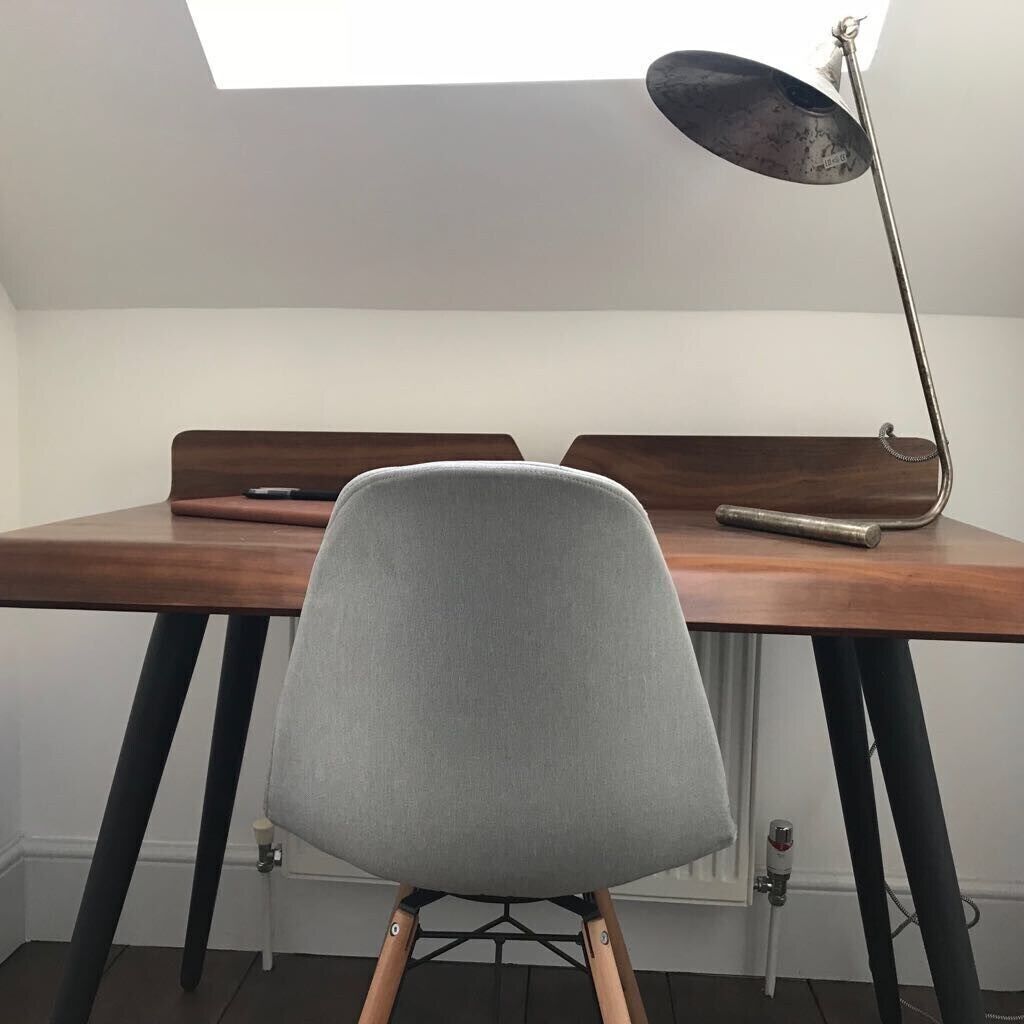 A desk with a grey chair, a lamp, and a wooden desk surface.