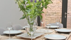 A dining table set with plates, glasses, and a vase with flowers. - Central Bath House Group Accommodation (Bath)