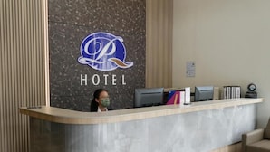 Un mostrador de recepción de hotel con un muro de mármol y un logotipo.