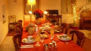 A dining room with a red tablecloth, wooden chairs, and a hanging light fixture.