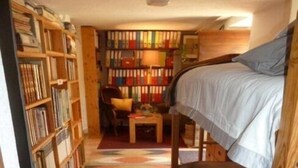 A cozy room with a bunk bed, a small desk, and a bookshelf filled with books.