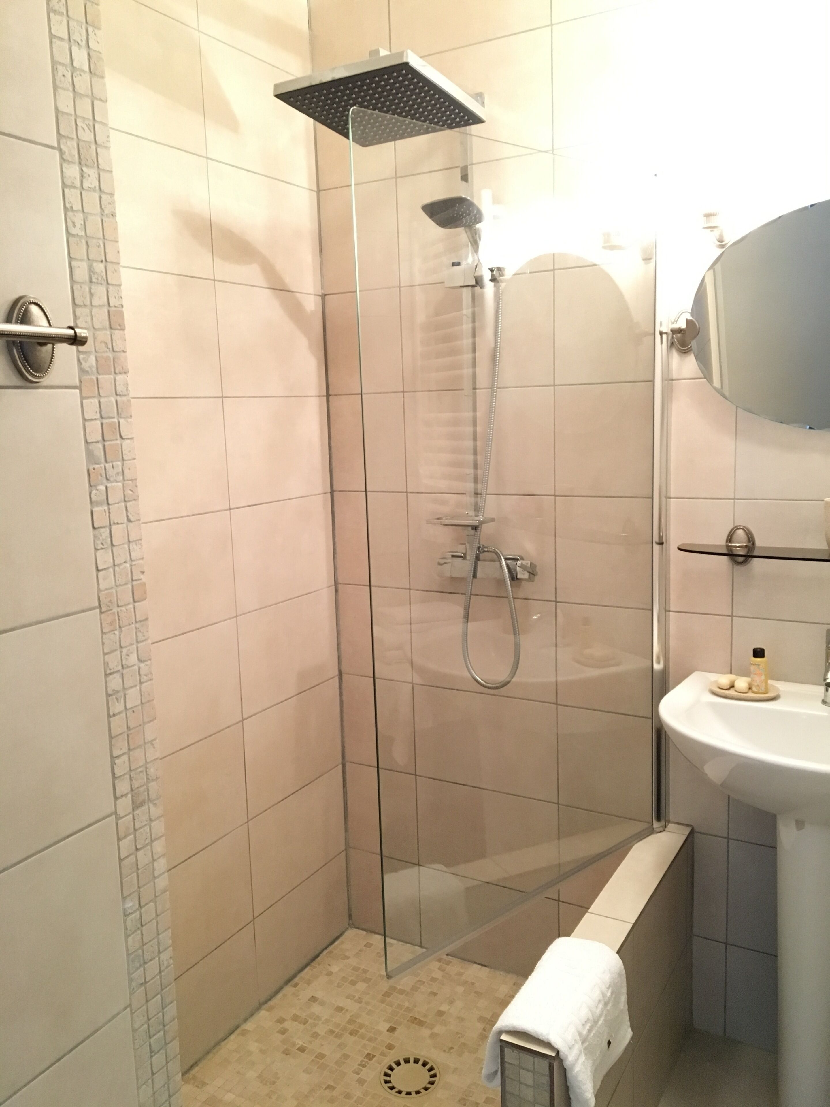A modern bathroom with a glass-enclosed shower, a white sink, and a mirror above the sink.