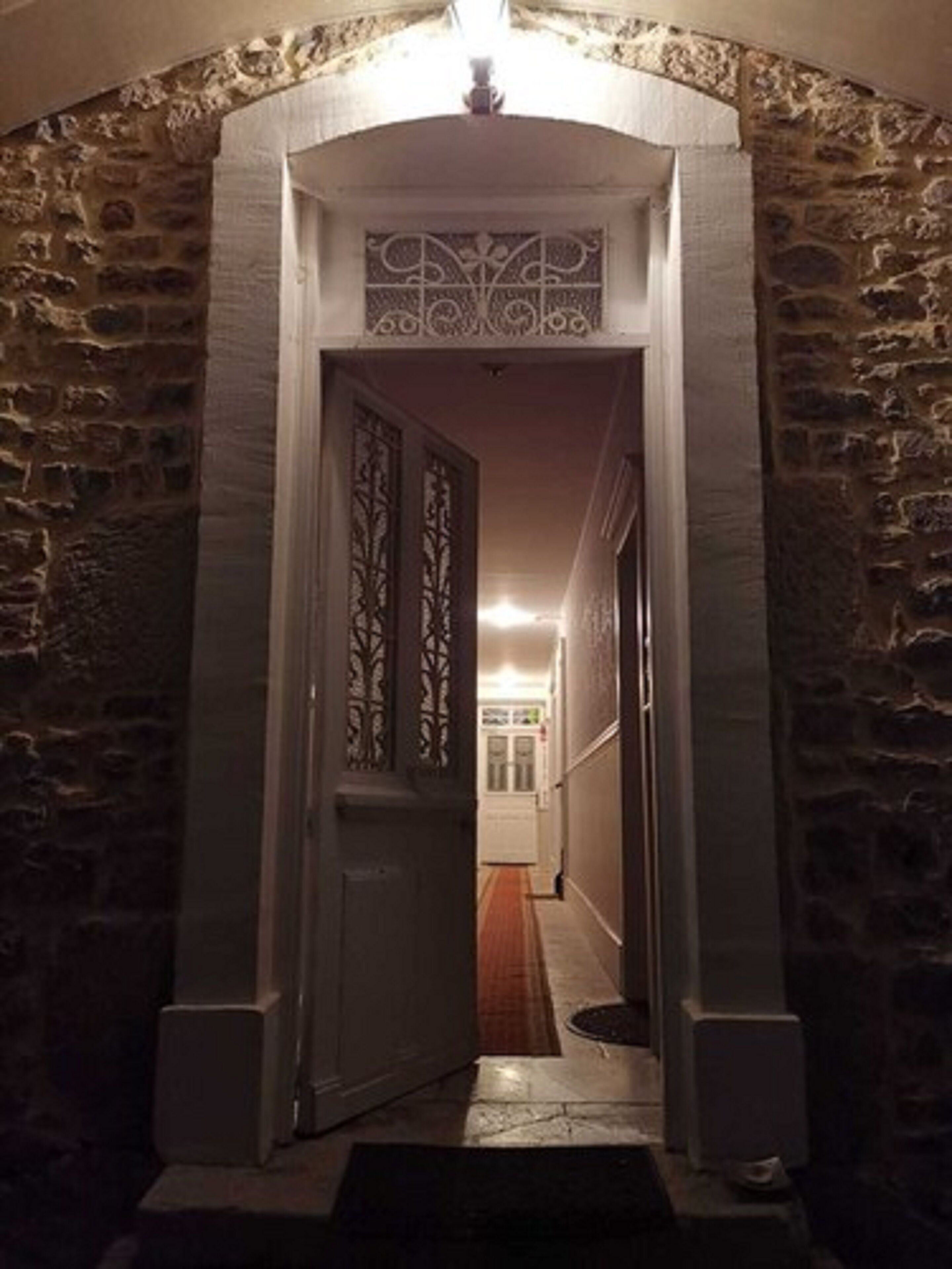 A stone archway leading into a hallway with a decorative metal gate.