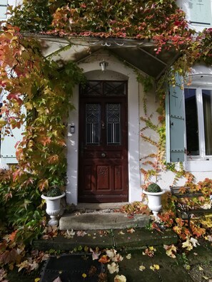 A house with a dark brown door, white walls, and a covered entrance. - Presbytere (Sauville)