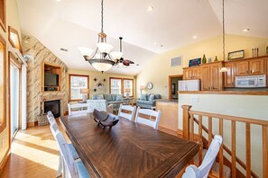 Cozy living area with a large dining table, stone fireplace, and comfortable seating.