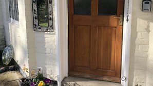A wooden front door with a glass panel, a metal doorbell, and a small step leading to the entrance. - Bron Hafren (Montgomery)