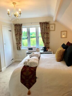 A bedroom with a bed, a window with curtains, a microwave, and a bedside table with a kettle. - Bron Hafren (Montgomery)