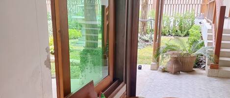 Una habitación con un banco de madera, una mesa con un juego de mesa, una planta en maceta y vistas a un jardín y una escalera.