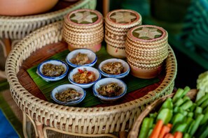 A wicker tray with bowls of food and a basket of vegetables.