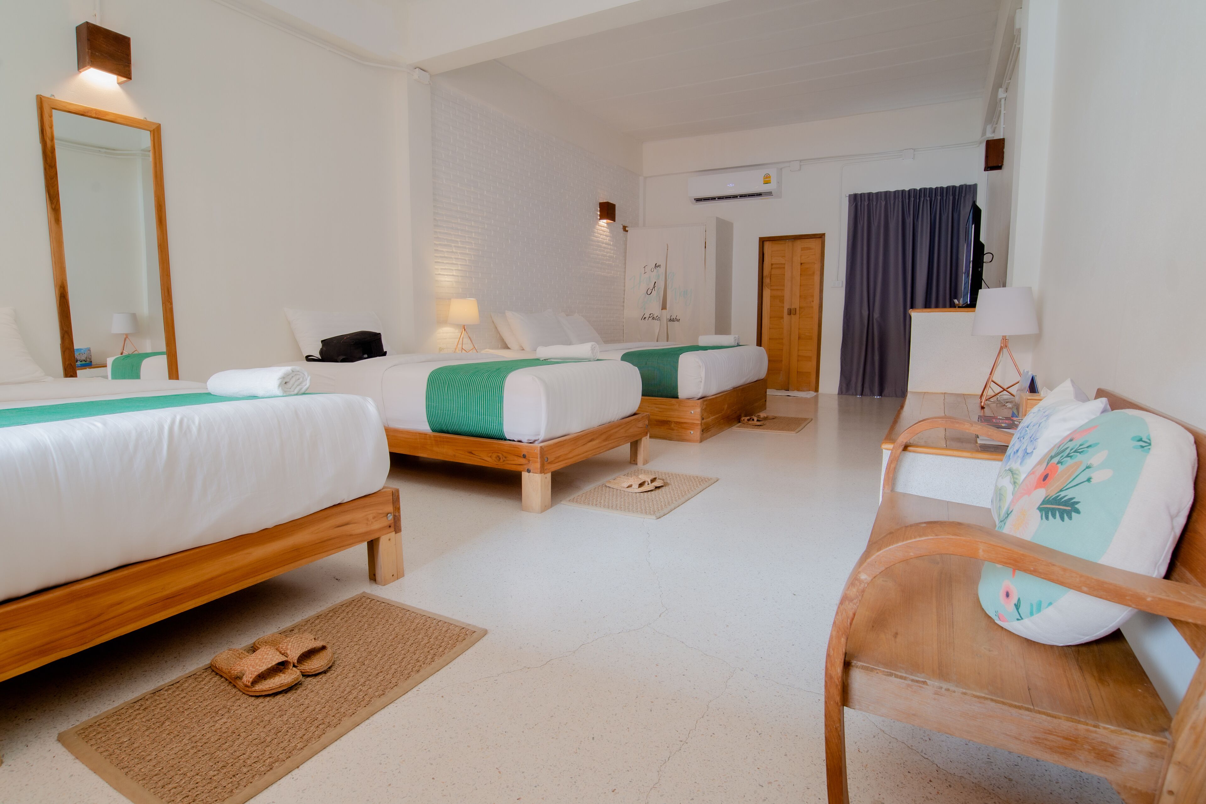 A hotel room with two wooden beds, a desk, a chair, a mirror, and a wardrobe.